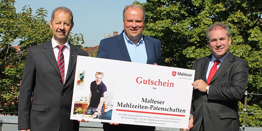 Foto: Malteser Bezirksgeschäftsführer Dieter Wünsche (l.) und Malteser Kreisbeauftragter Christoph Graf von Brühl (r.) überreichen einen Gutschein über Malteser Mahlzeiten-Patenschaften für die Bürgerinnen und Bürger des Landkreises an Landrat Christoph Göbel (m.).