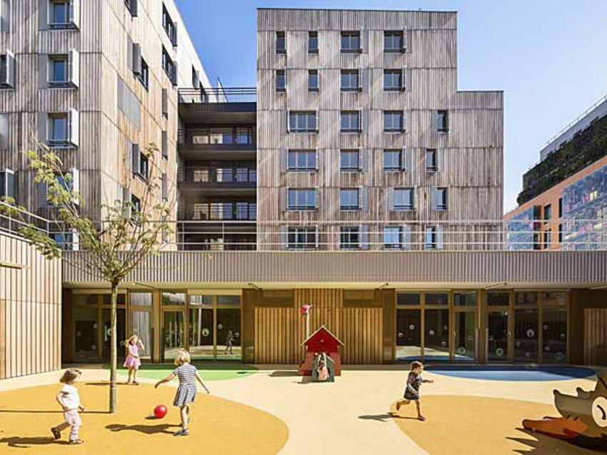 Foto: Spielende Kinder im Innenhof mehrerer hochwertiger Wohngebäude in Holzoptik.